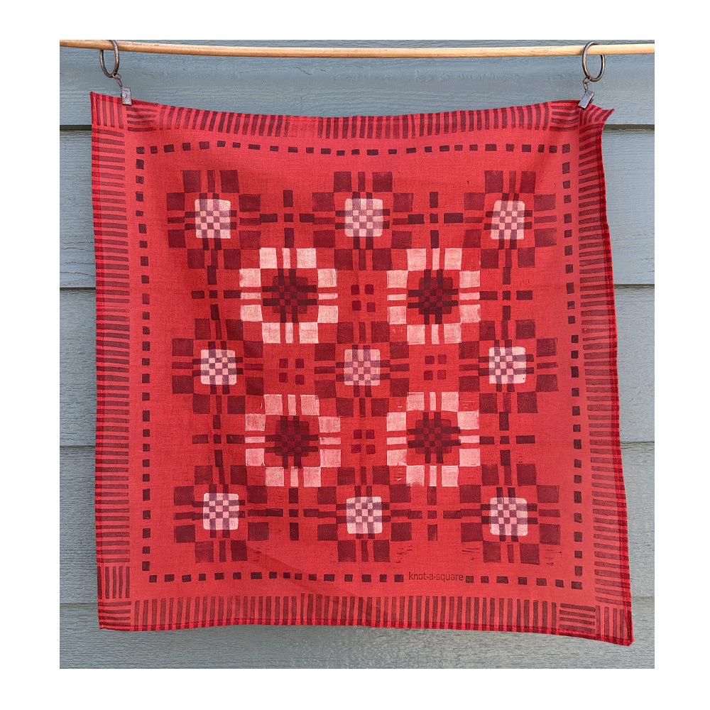 Vibrant red patterned bandana with a modern patchwork design, hanging on a clothesline