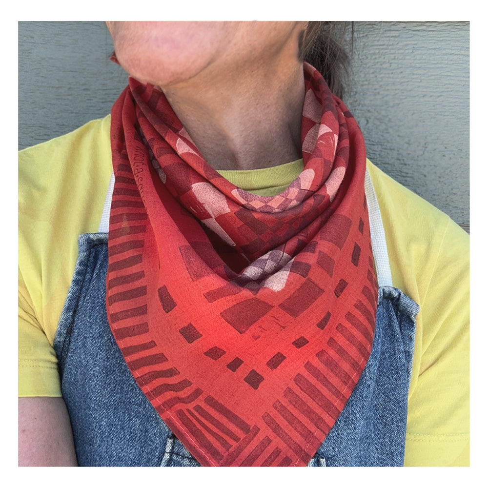 Vibrant red patterned bandana with a modern patchwork design, worn by a woman wearing an apron