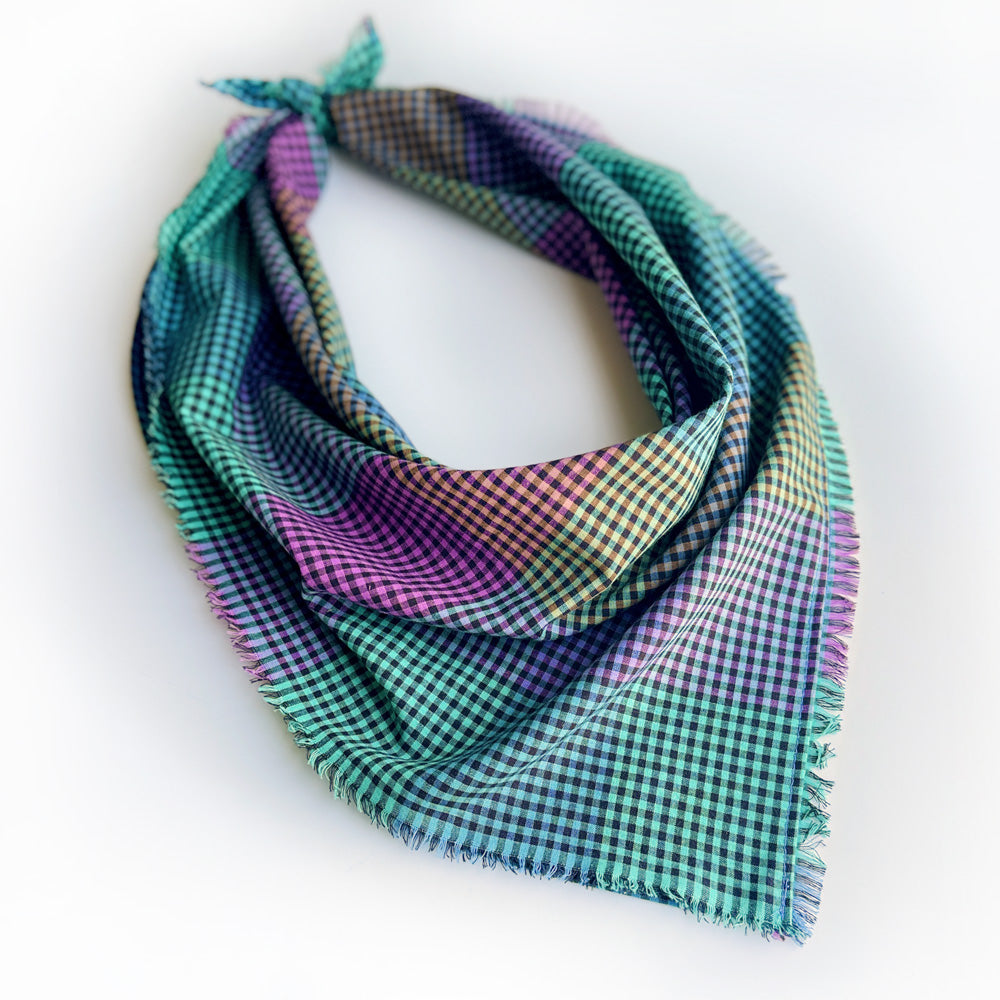 multi color gingham scarf tied for display, with fringed edges on a white background.  The gingham check pattern of teal, purple, green, and blue.