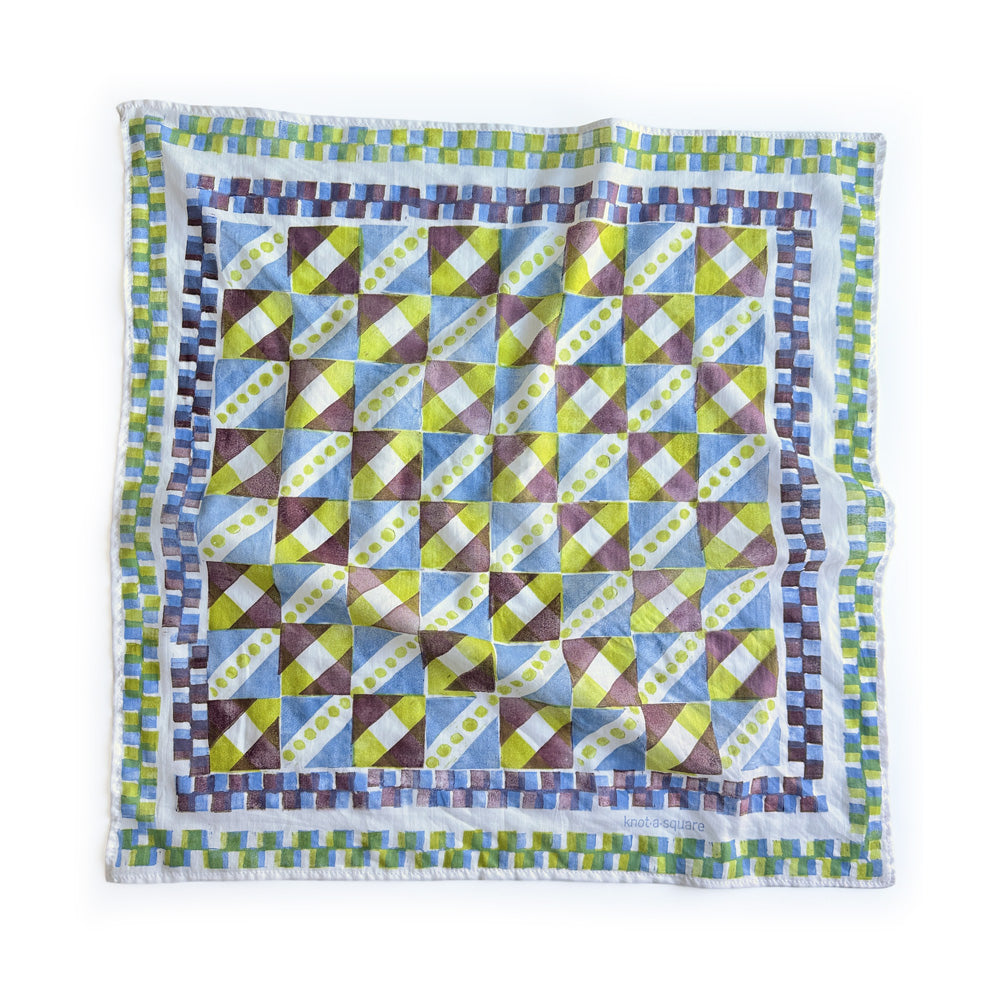 A square bandana with a geometric patchwork pattern in blue, green, yellow, and brown, finished with a checkered border. 