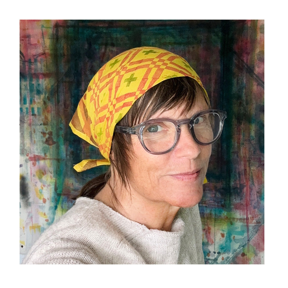 A Smiling woman wearing a yellow geometric patterned headscarf against a colorful abstract background