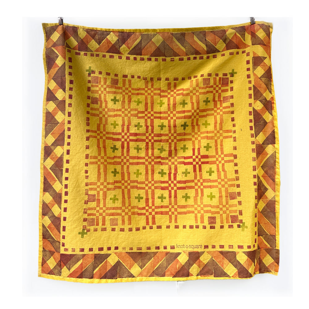 Hand printed warm yellow bandana with a boxy geometric pattern on a white background