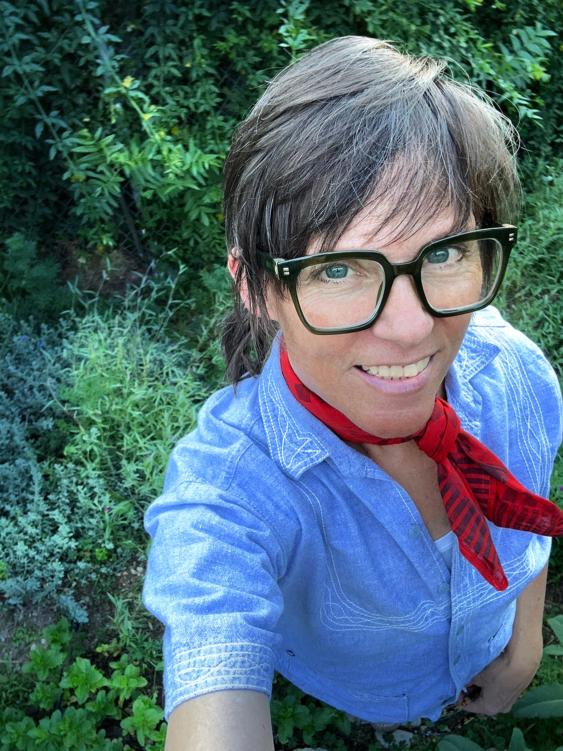 woman wearing glasses and a red bandana in a verdant natural setting